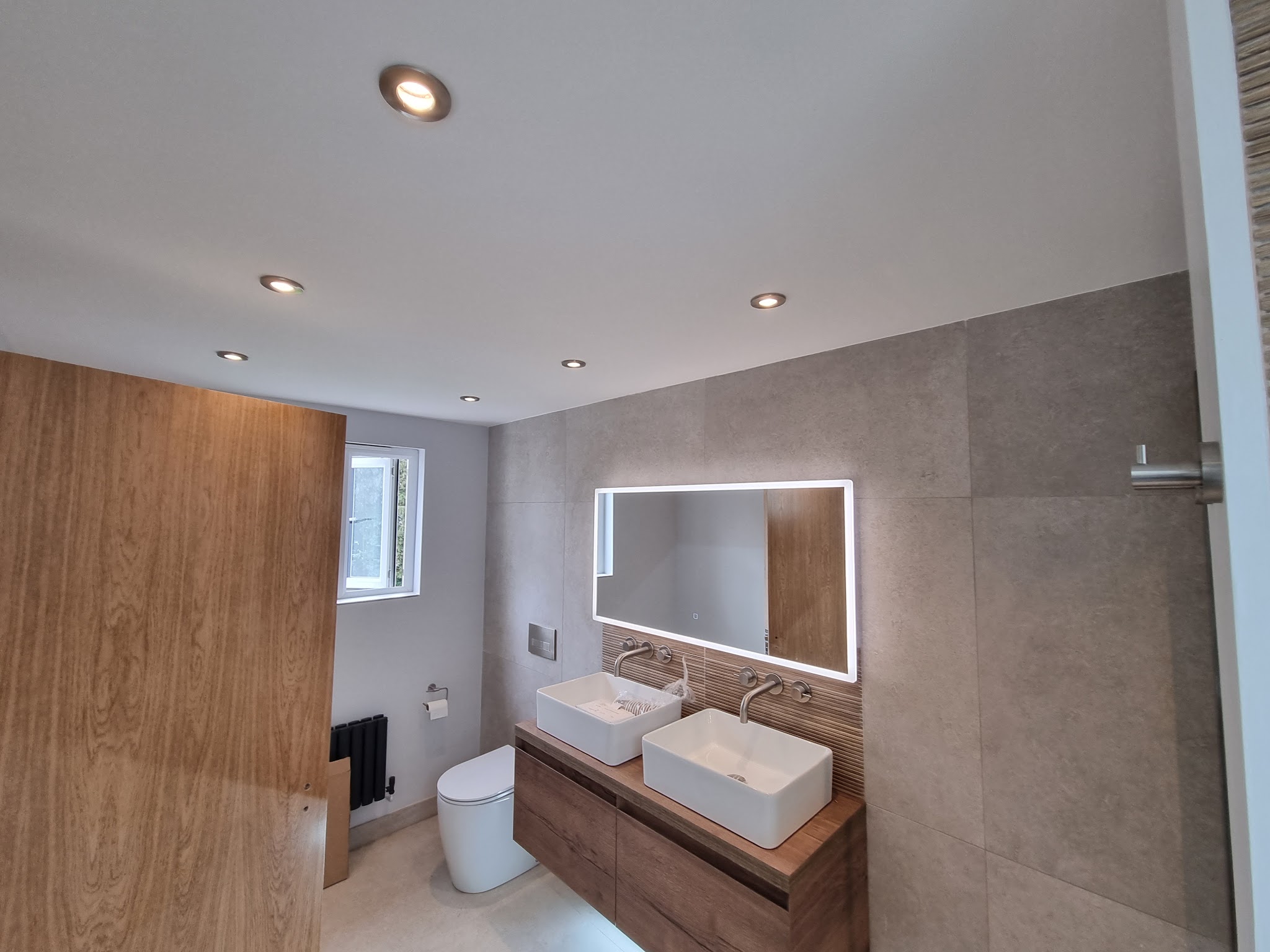 Finished bathroom with downlights, an illuminated mirror and twin basins