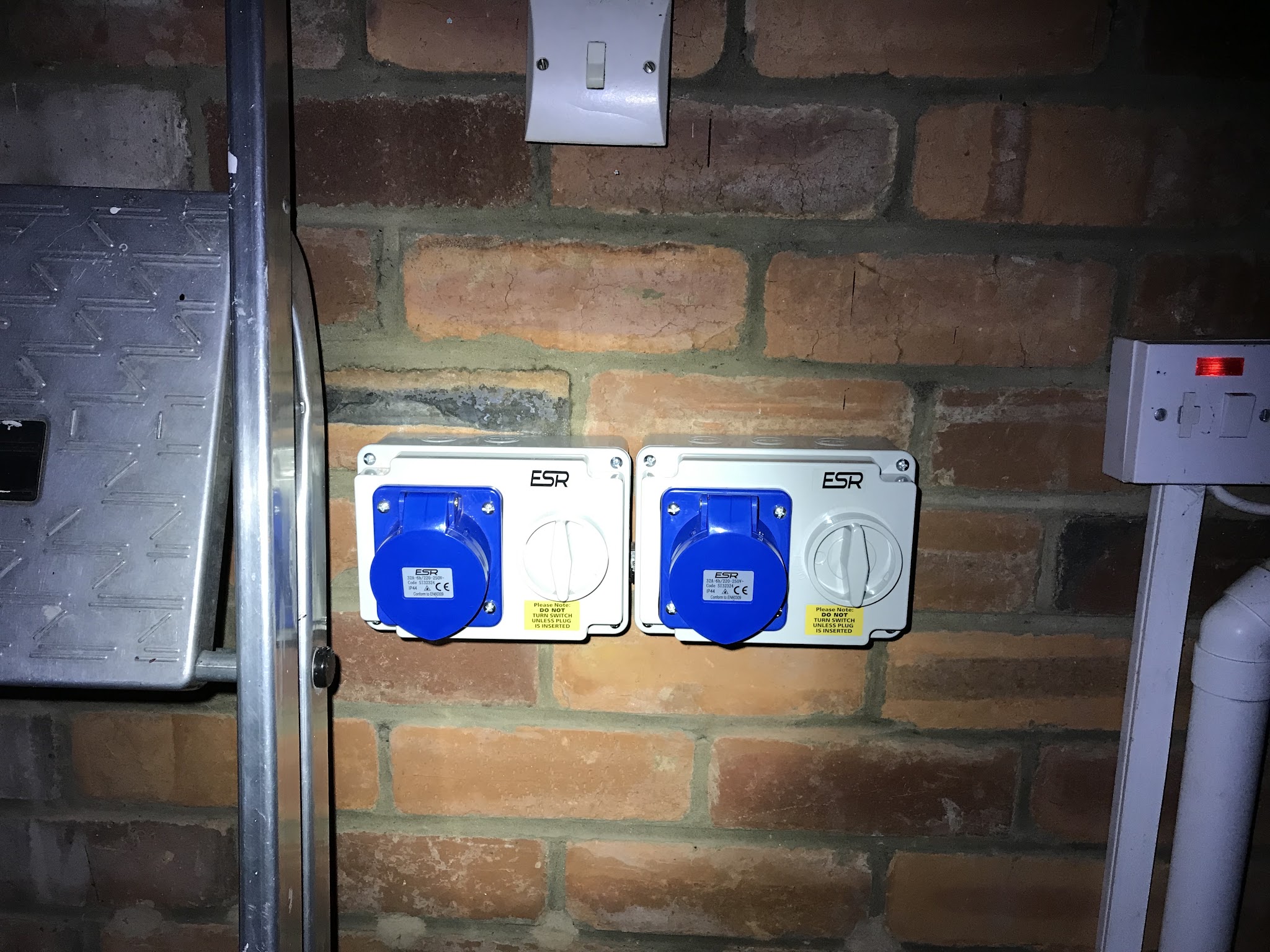 Two blue 16 amp outdoor commando sockets mounted on a brick wall